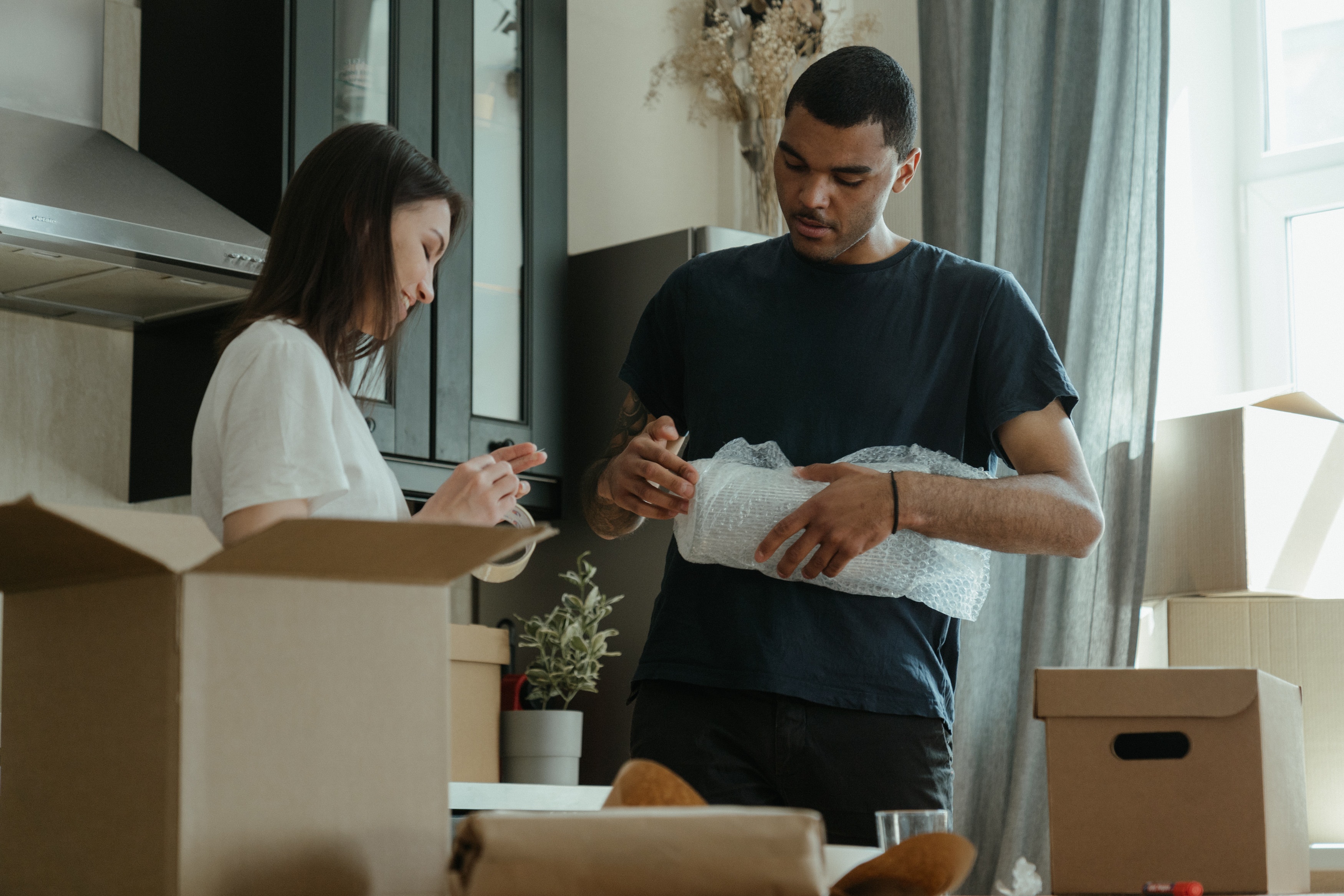 Couple standing in kitchen packing boxes to move house