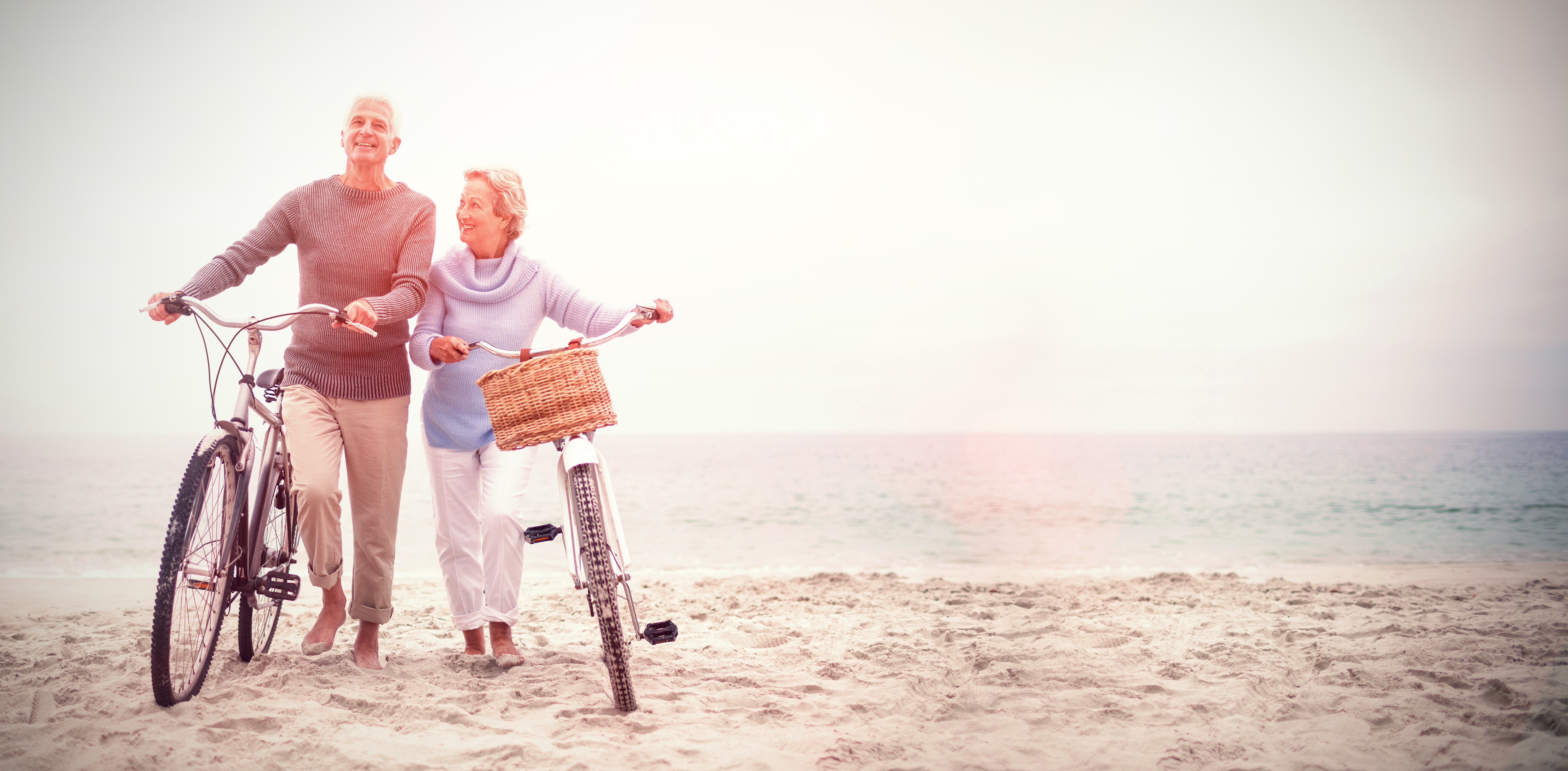 Older couple riding bikes on the beach