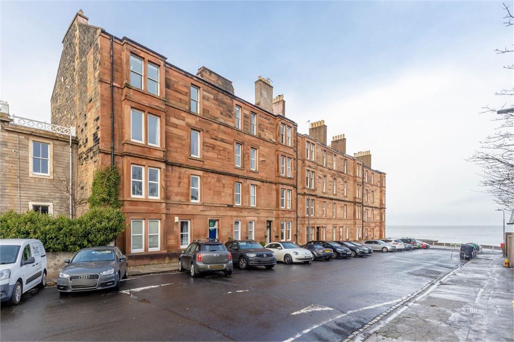 A block of tenement flats with a view of the sea behind them.