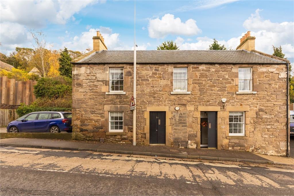 The exterior of stone built-house on a sloped road.