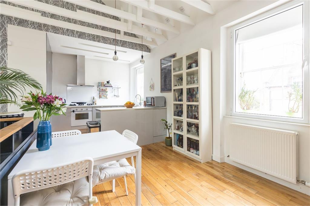 A spacious open plan kitchen with white walls and light grey cabinets.