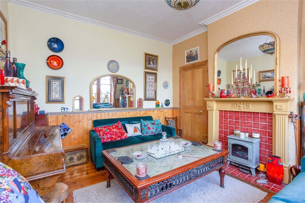 A vibrant living room with colourful interiors including a red fireplace, dark green sofa, and piano.