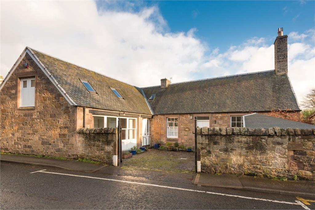 A stone built house pictured from across the road.