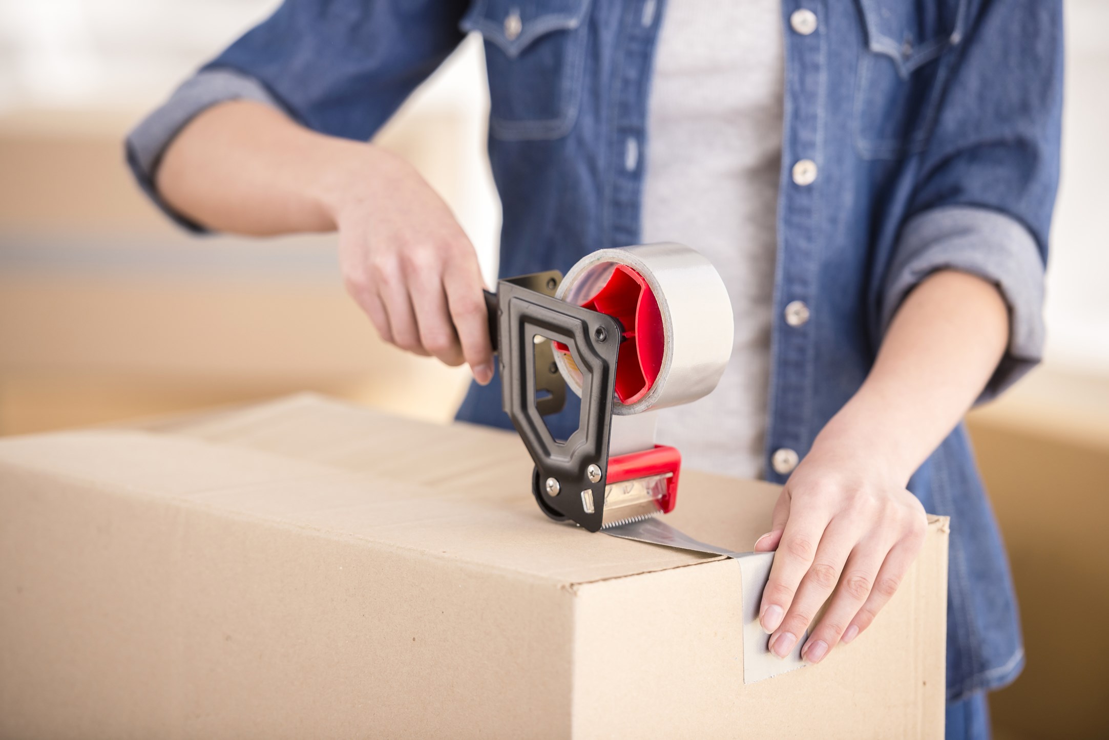 woman's hands taping box closed